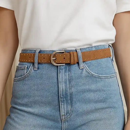 Cinturón de ante marrón con remaches y hebilla dorada colocado en vaqueros claros