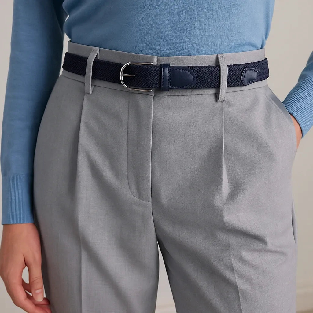 mujer con jersey azul y cinturón trenzado azul marino sobre pantalón gris claro