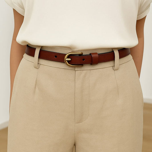 cinturón marrón con hebilla ovalada dorada sobre pantalón beige claro