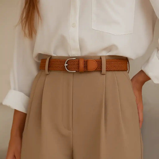 mujer con camisa blanca y cinturón marrón trenzado sobre pantalón beige de pinzas