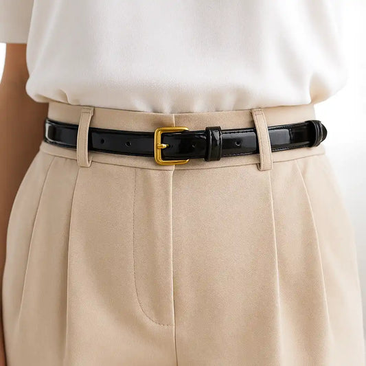 mujer con pantalón beige y cinturón negro de charol con hebilla dorada