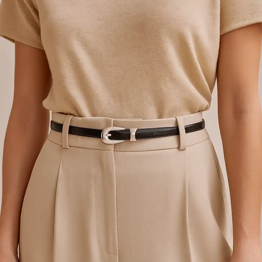 Cinturón negro de cuero fino colocado sobre pantalón de vestir beige