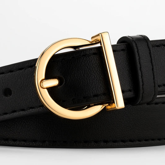 primer plano de la hebilla dorada de un cinturón negro de símil cuero mostrando su textura y costuras