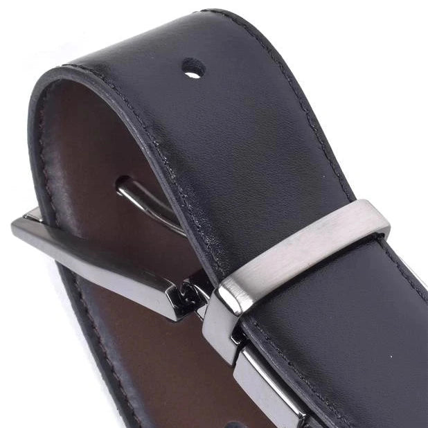 detalle de hebilla metalica en niquel sobre cinturon de piel negro con reverso marron