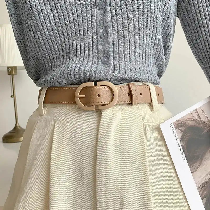 cinturón negro con hebilla metálica usado con falda plisada beige y top sin mangas