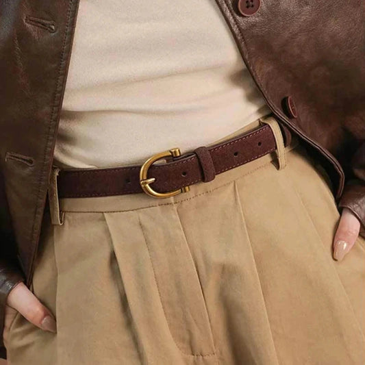 cinturón marrón de ante fino con hebilla dorada ajustado en pantalón beige